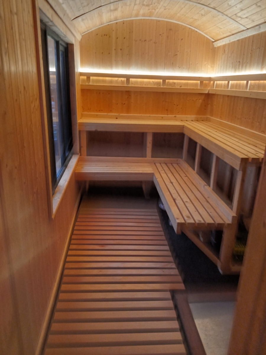 Inside the shepherd's hut sauna: tiered timber benches under a curved wooden roof